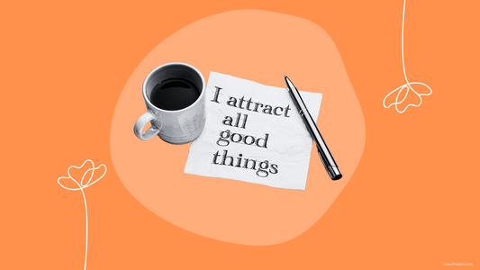 Image of a coffee cup, a pen, and a napkin with the handwritten phrase 'I attract all good things' on a bright orange background, promoting the practice of self-love affirmations to cultivate positivity and self-worth.