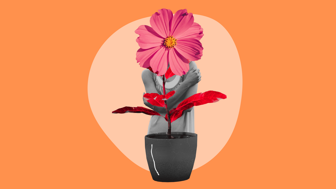 A person hugging themselves with a pink flower as their head, symbolizing self-love and growth, stands behind a black pot with red leaves against an orange and beige background.