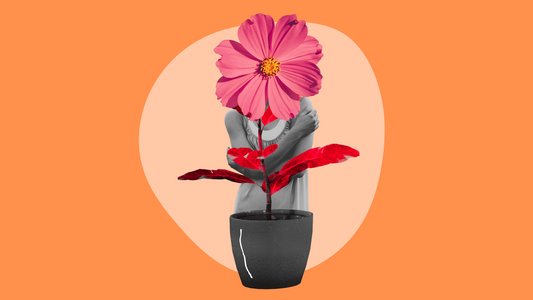 A person hugging themselves with a pink flower as their head, symbolizing self-love and growth, stands behind a black pot with red leaves against an orange and beige background.