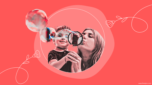 A joyful mother blowing bubbles with her young child, symbolizing the importance of self-love for mothers through moments of connection and care.
